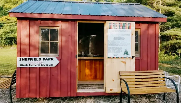 A small red house with a door open.