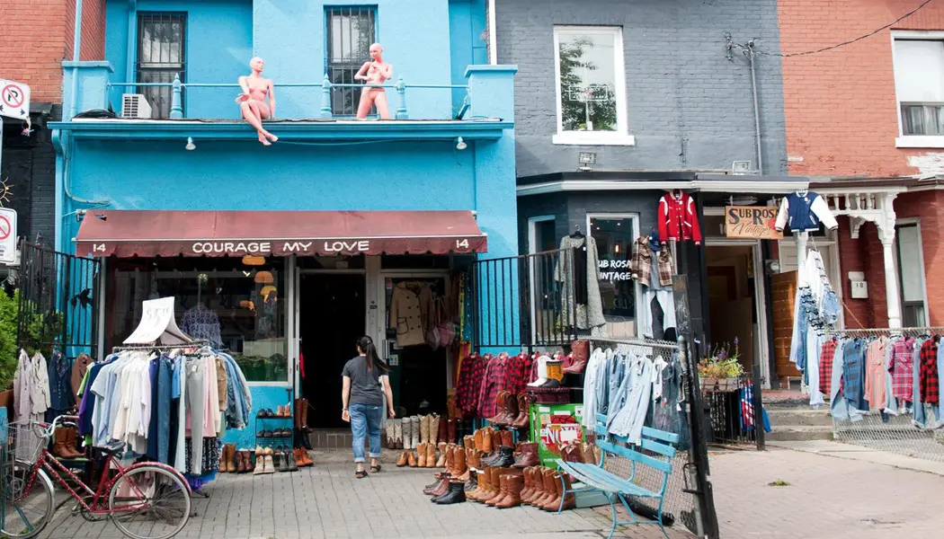 Une femme passe devant des vêtements et des chaussures d'occasion exposés devant une boutique vintage du marché de Kensington.