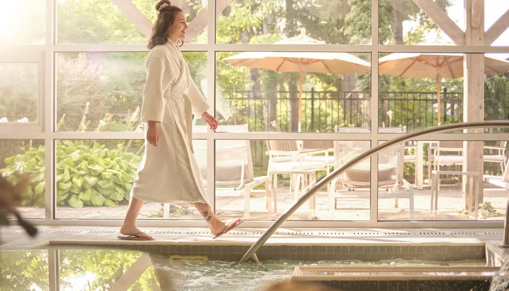 Une femme en peignoir éponge se promène dans la piscine intérieure du spa de Langdon Hall.