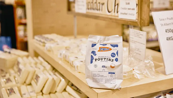 Un sac de mélange de sauce à poutine est posé sur une étagère avec du fromage de la Coopérative fromagère de St-Albert.