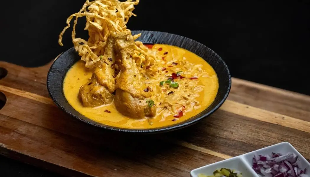 Un bol de curry de poulet est servi avec différentes garnitures dans un restaurant thaïlandais de London, en Ontario.