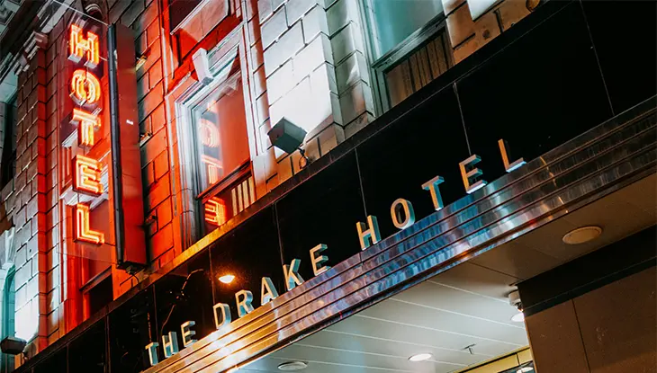 Neon-lit hotel entrance glowing at night with a red vertical sign.