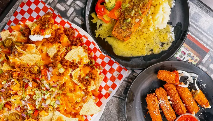 Nachos, saumon avec purée de pommes de terre et bâtonnets de mozzarella servis sur une table.