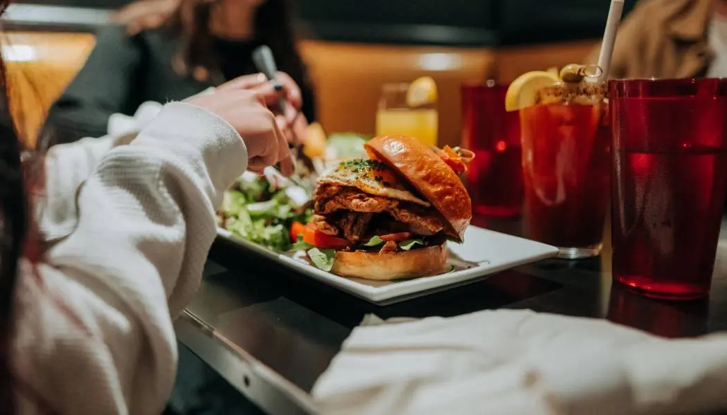 Un hamburger juteux garni de nombreux ingrédients supplémentaires, servi avec une salade et une boisson fruitée.