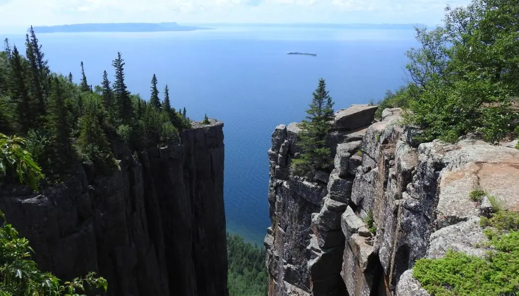 View of Lake Superior between two massive, towering rock cliffs from the top of the Sleeping Giant hiking trail.