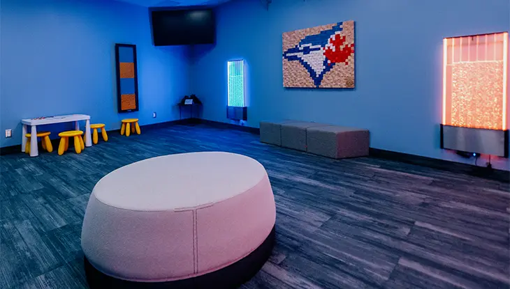 Interactive sensory room with soft seating, illuminated bubble walls, and Toronto Blue Jays artwork designed for calming experiences.