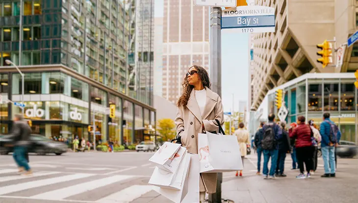 Mujer caminando por la calle llevando varias bolsas de la compra.