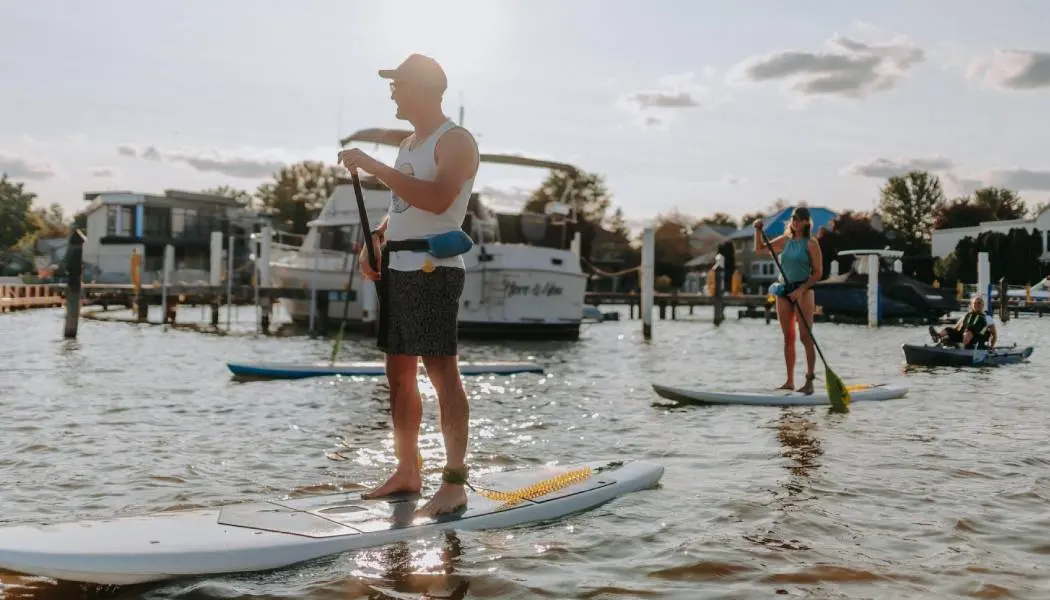 Deux personnes debout sur des planches à pagaie, suivies d’une personne en kayak, au port de plaisance de Windsor.