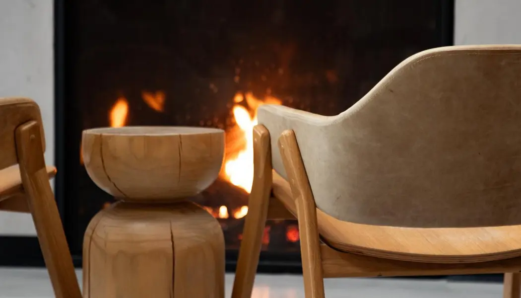 Deux chaises et un tabouret en bois sont disposés devant une cheminée au Wander the Resort, dans le comté de Prince Edward.