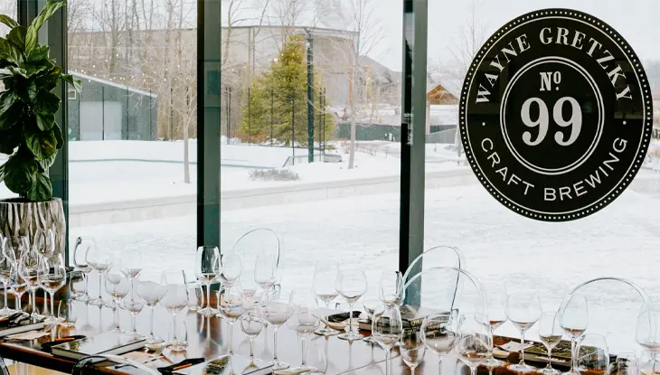 A table set with several wine glasses for a wine tasting, in front of the skating rink.