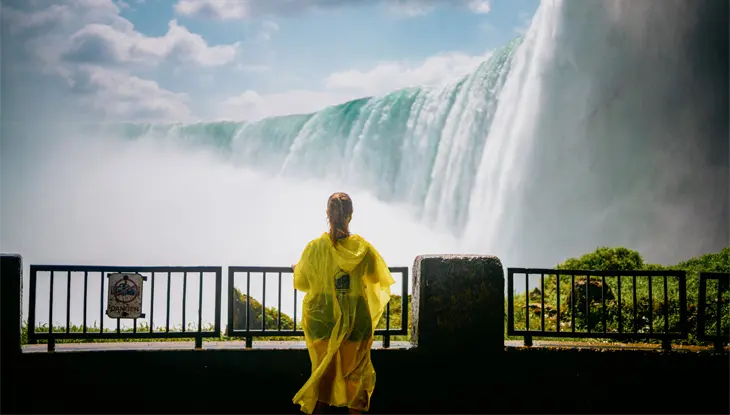 Une femme portant un poncho de pluie devant les chutes Niagara.