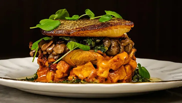 Un plat raffiné composé de légumes empilés et d'un morceau de poisson par-dessus.