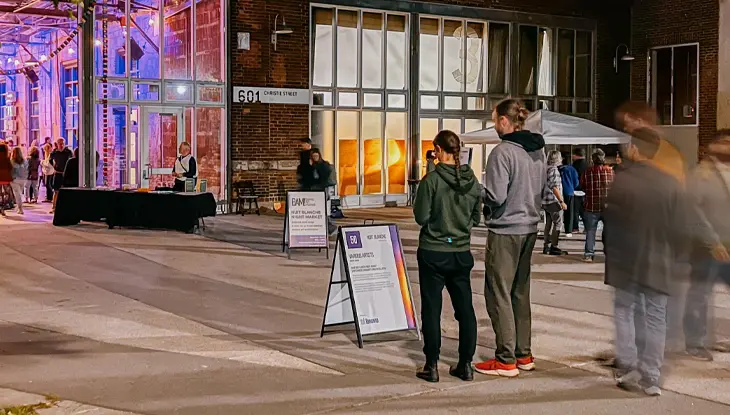 Des personnes observant les diverses installations artistiques mises en place pour la Nuit Blanche à l’extérieur et à l’intérieur de Wychwood Barns.
