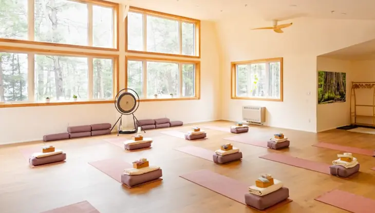 Yoga studio with mats, cushions and natural light from large windows.